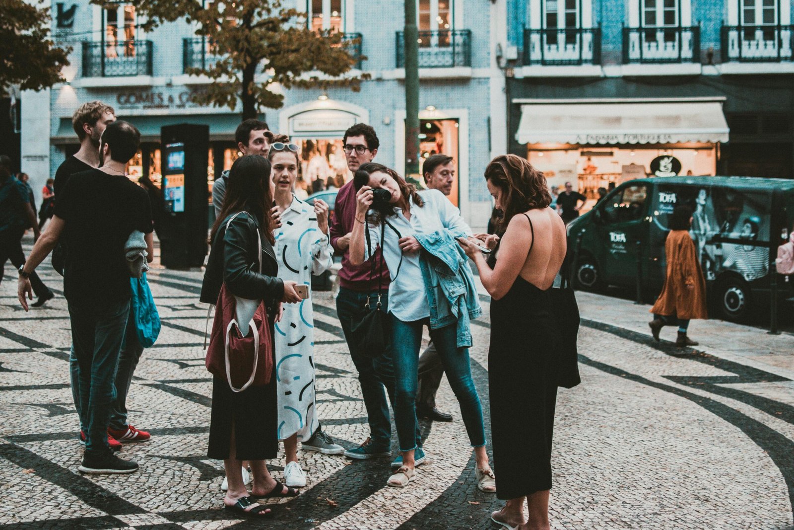 Casual group of tourists socializing and taking photos on a bustling European street.