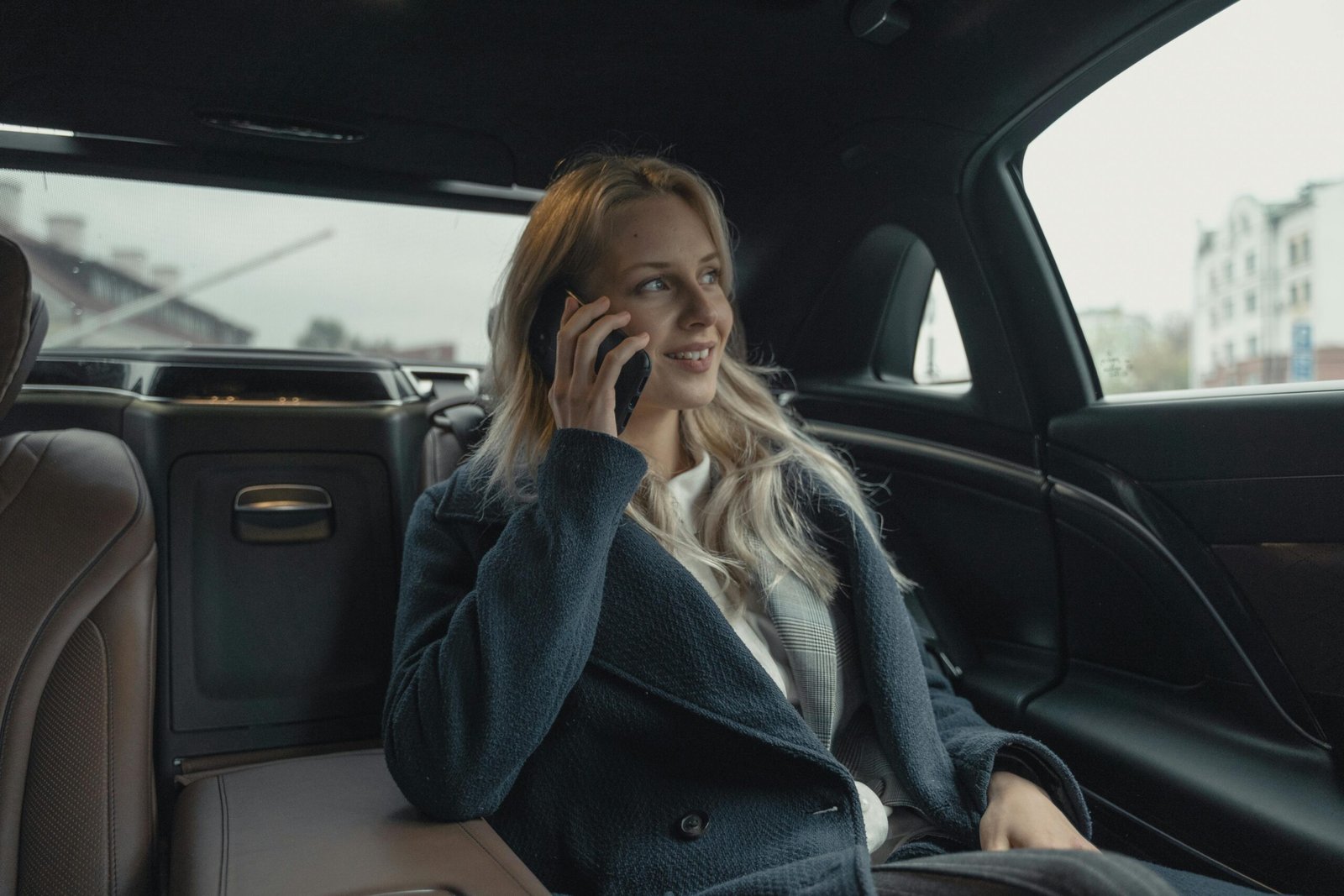 Businesswoman talking on phone while sitting in a luxury car, portraying professionalism and leadership.